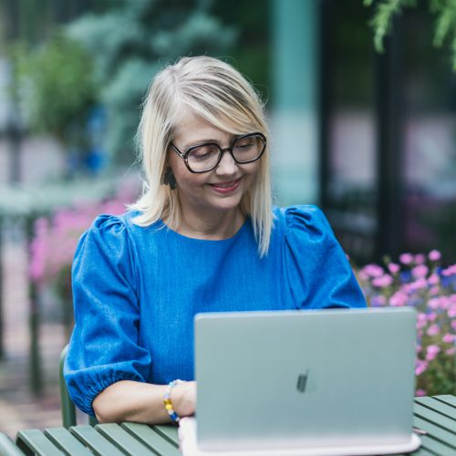 Dette billede viser ejeren af ActionBetween, hun sidder udenfor med sin computer foran sig.